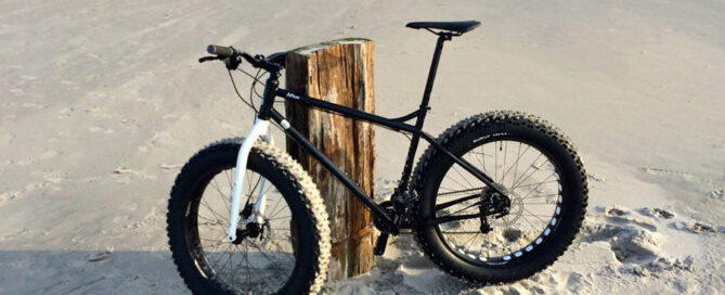 Ein Mountainbike angelehnt an einen rustikalen Holzpflock am Strand